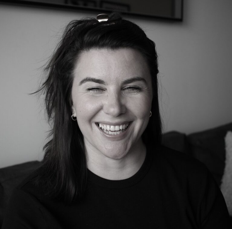 Laura Stannard laughing with her eyes closed, in a black and white photo